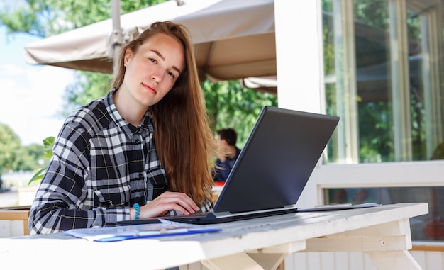 Foto estudiante joven atractivo que usa la computadora portátil afuera