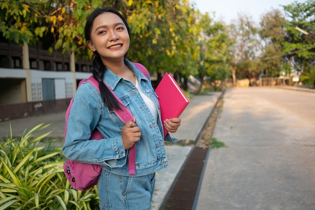 Estudiante joven con libro rosa de pie en schoo