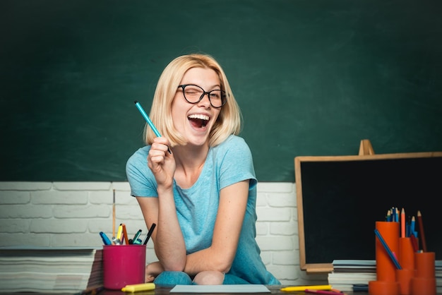 Estudiante joven maestro en gafas sobre fondo de pizarra verde estudiante de escuela retrato de una hembra