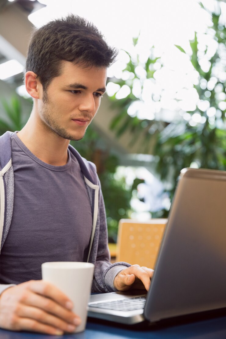 Foto estudiante joven que usa su computadora portátil en café