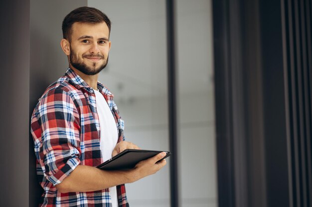 Estudiante joven que usa la tableta fuera de la universidad