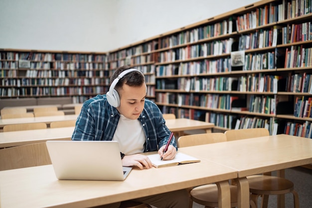 Un estudiante de lección en línea que estudia en la universidad usa una computadora portátil y un chat de video con auriculares