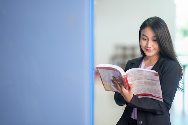 Foto una estudiante lee un libro en la biblioteca de niñas asiáticas buscando información en el trabajo de la biblioteca de la universidad de libros