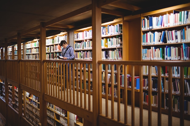 Estudiante leyendo libro en la biblioteca de la universidad