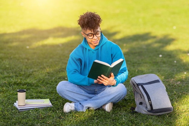 Estudiante leyendo un libro en la hierba