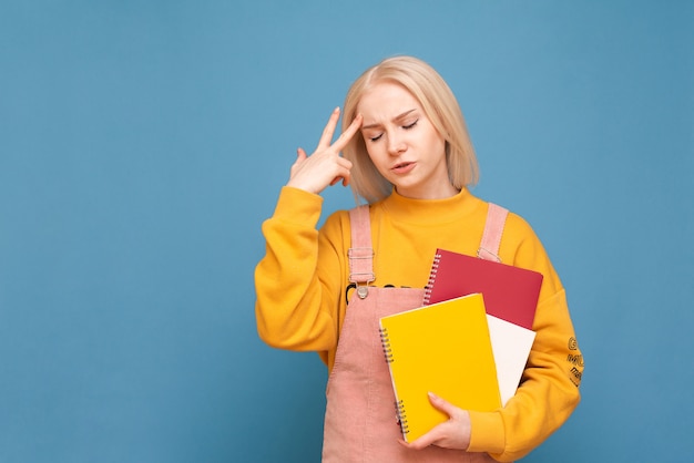 estudiante con libros y cuadernos en sus manos se encuentra en azul con los ojos cerrados