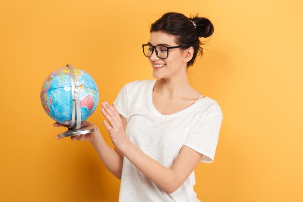 Estudiante linda joven bonita que sostiene el globo que mira a un lado.