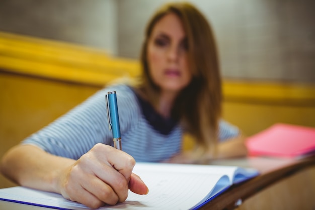 Foto estudiante madura tomando notas en la sala de conferencias