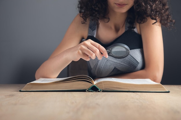 Estudiante manos sosteniendo lupa y libro