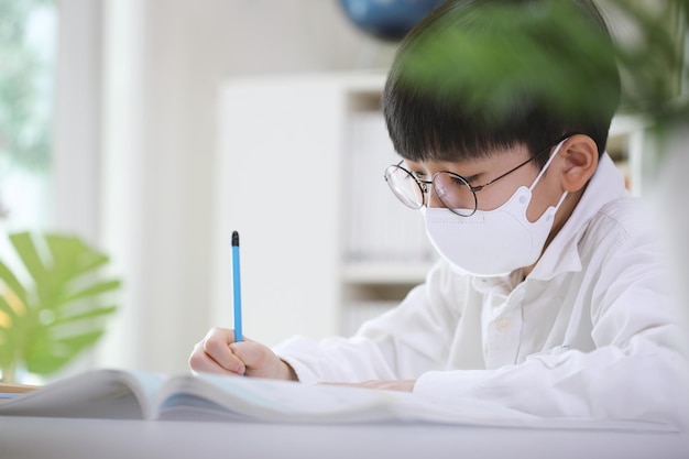 Un estudiante con una máscara sentado en un escritorio y estudiando duro mientras se concentra en estudiar