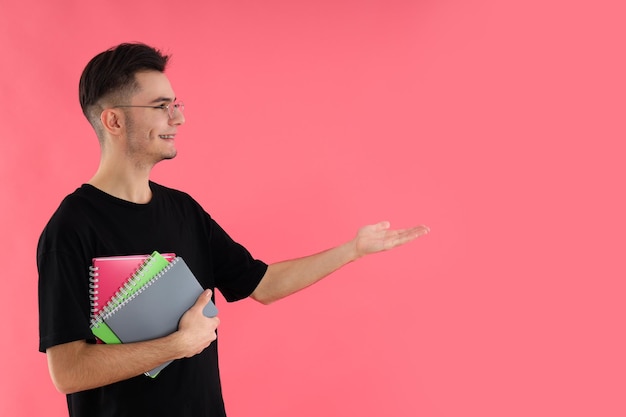 Estudiante masculino con cuadernos sobre fondo rosa