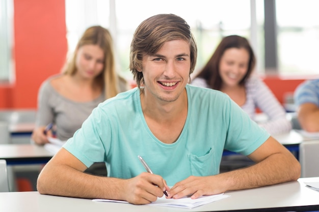 Estudiante masculino escribiendo notas en el aula