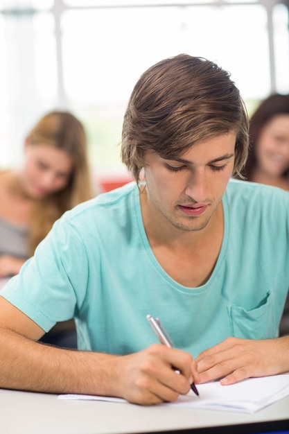 Estudiante masculino escribiendo notas en el aula