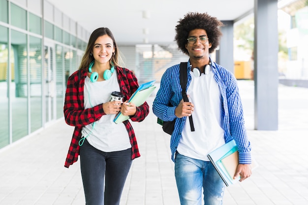 Foto estudiante masculino y femenino con libros en la mano caminando en el pasillo de la universidad