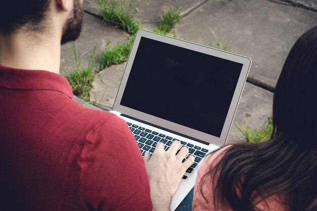 Estudiante masculino joven que usa la computadora portátil al aire libre.