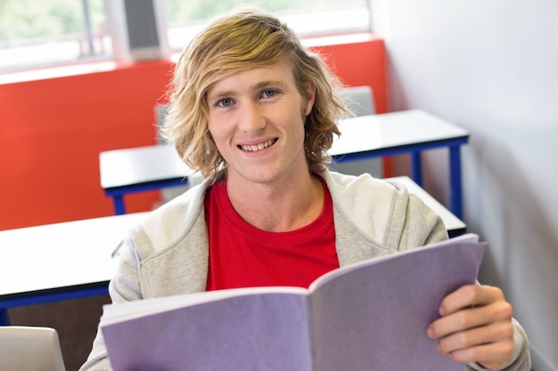 Estudiante masculino leyendo notas en el aula