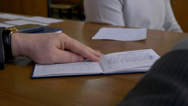 Estudiante masculino con un maestro en el aula El maestro escribe la evaluación en el libro de calificaciones