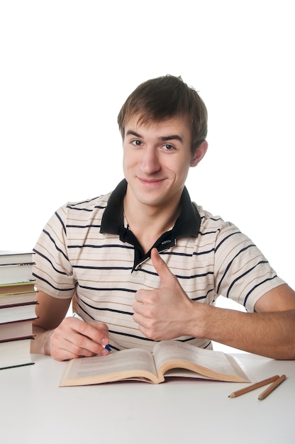 Estudiante masculino en la mesa con un montón de libros sobre blanco