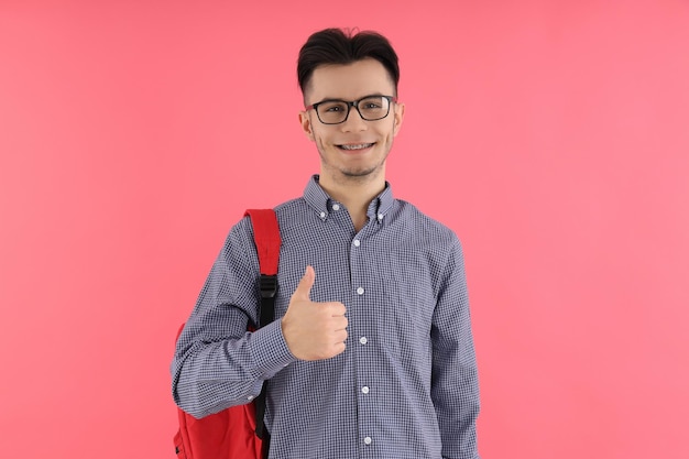 Estudiante masculino con mochila sobre fondo rosa
