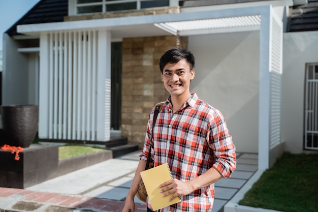 Estudiante masculino de pie frente a su casa