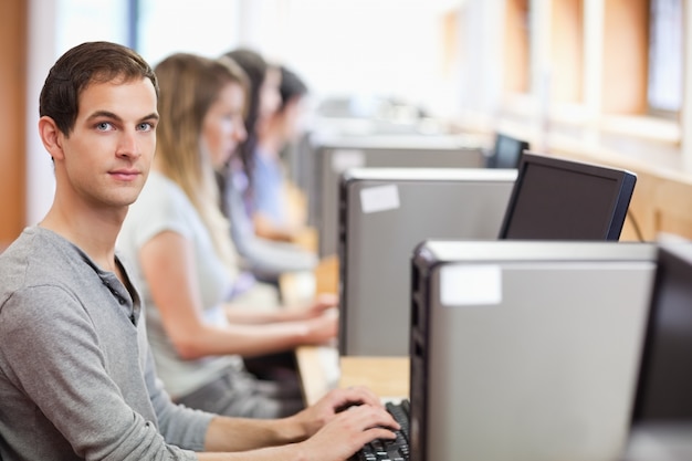 Estudiante masculino posando con una computadora