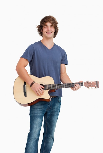 Estudiante masculino posando mientras sostiene una guitarra