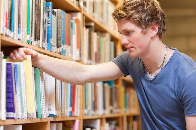 Estudiante masculino que elige un libro