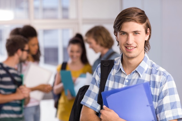 Estudiante masculino que sostiene la carpeta en la universidad