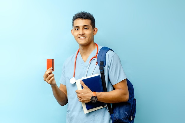 Estudiante de medicina con mochila sosteniendo libros y una tarjeta de crédito roja mirando a la cámara