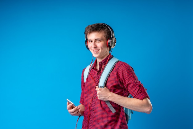 Estudiante con mochila, teléfono móvil y auriculares escuchando música.