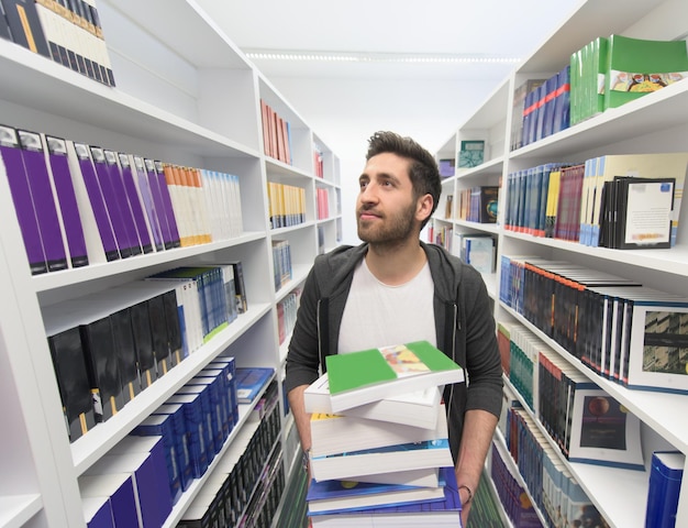 Estudiante con un montón de libros en la biblioteca de la escuela Trabajo duro y concepto de persistencia