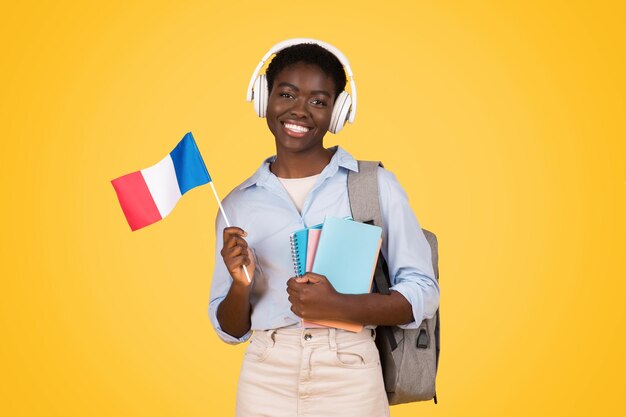 Foto estudiante mujer con bandera francesa y auriculares