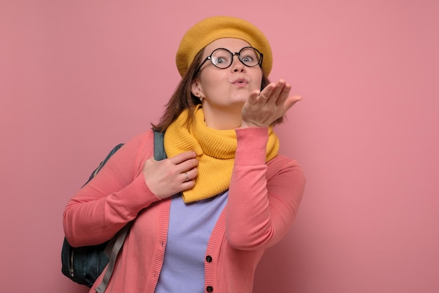 Estudiante mujer estudio de pie aislado sobre fondo rosa soplando beso de aire