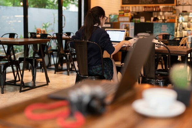 Estudiante de mujer joven que trabaja con la computadora portátil en café.