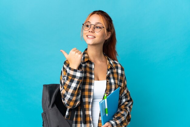 Estudiante mujer rusa aislada en azul apuntando hacia el lado para presentar un producto