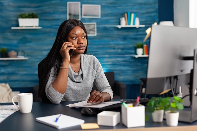 Estudiante negro sentado en la mesa de escritorio en la sala de estar trabajando en la tarea de la escuela secundaria