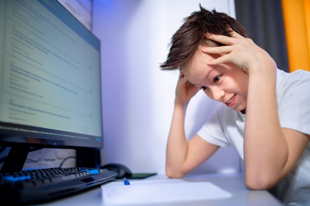 Estudiante de niño de escuela que estudia en casa. Niño estresado con dolor de cabeza para pruebas o exámenes en la computadora. Lecciones de aprendizaje. Concepto de sistema educativo.