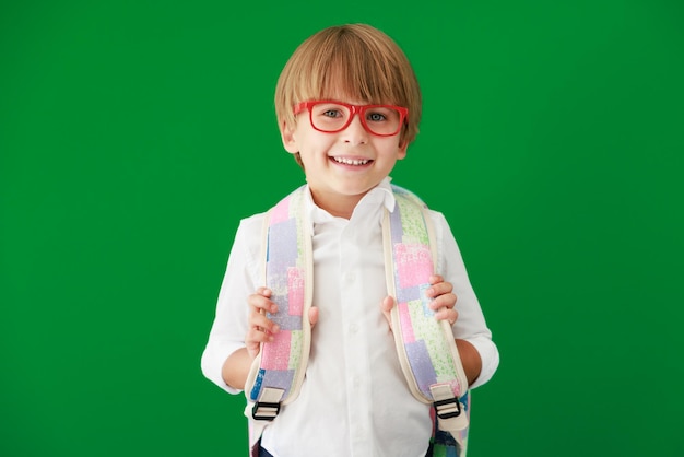 Estudiante de niño feliz contra pizarra verde