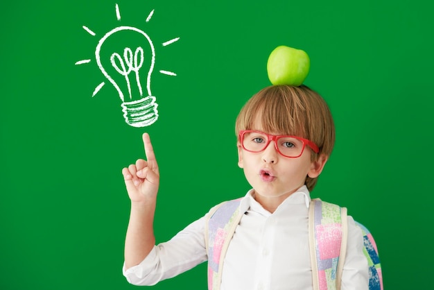 Estudiante de niño feliz contra pizarra verde