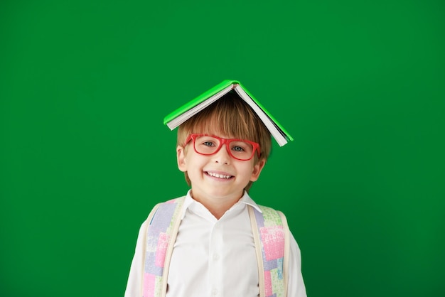 Estudiante de niño feliz contra pizarra verde