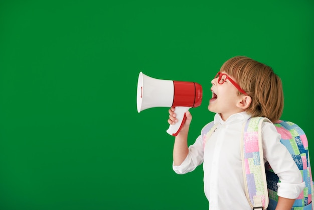 Estudiante de niño feliz contra pizarra verde