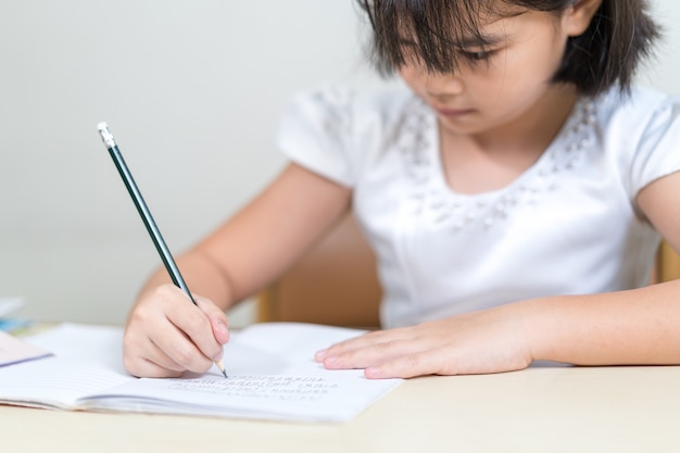 Estudiante de niños pequeños escribiendo en el cuaderno haciendo la tarea y el autoaprendizaje en casa