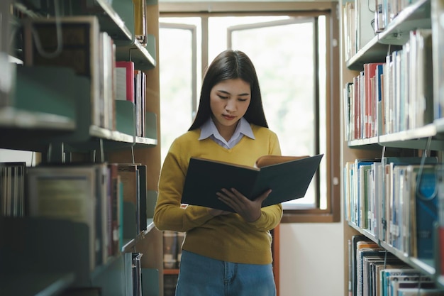 Estudiante de pie y leyendo un libro en la biblioteca