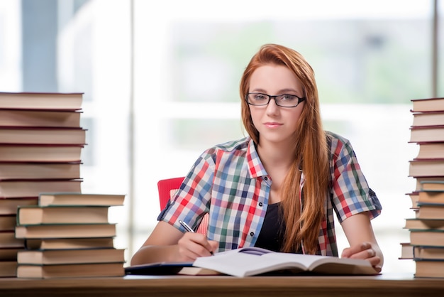 Estudiante con pilas de libros preparándose para los exámenes.