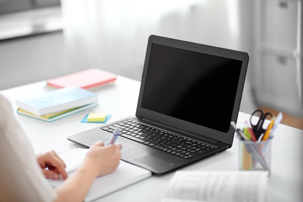 estudiante con portátil, cuaderno y libro