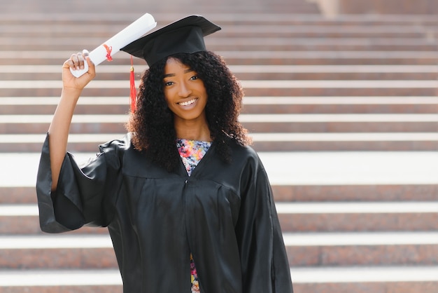 Estudiante de posgrado afroamericano alegre con diploma en la mano