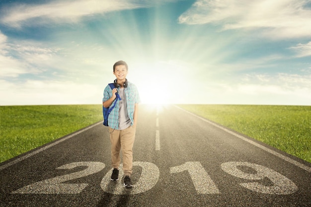 Un estudiante preadolescente feliz camina por encima del número 2019