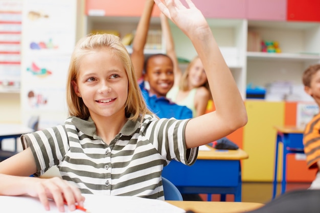 Estudiante pregunta y respuesta en el aula para la evaluación de aprendizaje y beca de educación con sonrisa Lección de niña inteligente y manos levantadas con cuestionario de examen de conocimiento o retroalimentación en la escuela primaria