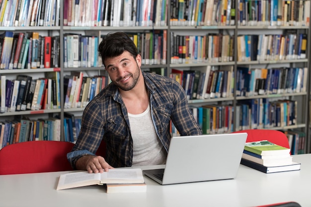 Estudiante preparando exámenes y lecciones de aprendizaje en la biblioteca escolar investigando en una computadora portátil y navegando por InternetxA en la biblioteca