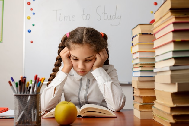 Estudiante de primaria aburrido leyendo un libro